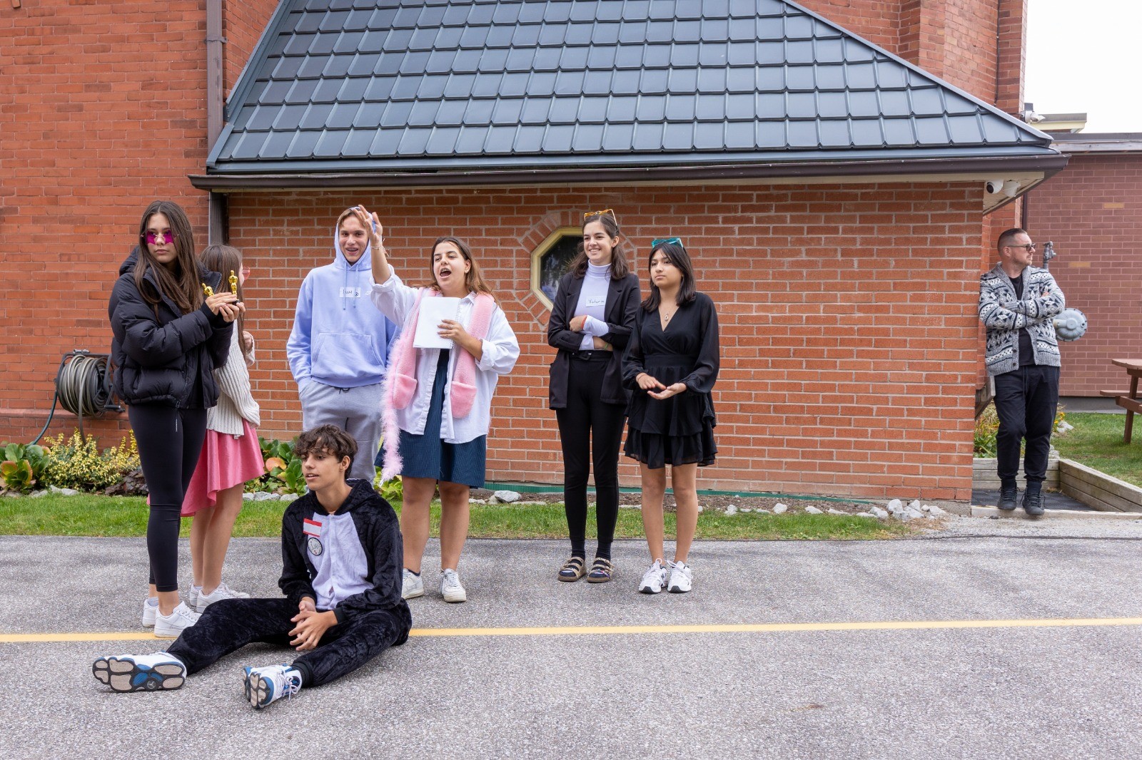 A group of teens standing outside a red brick church
