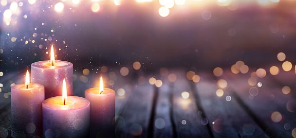 4 lit candles on a wooden background