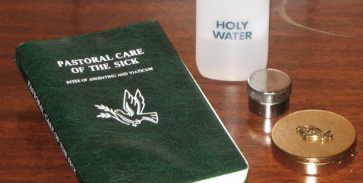 Green bible, holy water and 2 pyx on a wooden table