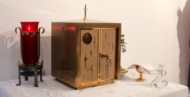 A gold tabernacle box with a red glass candle on the left