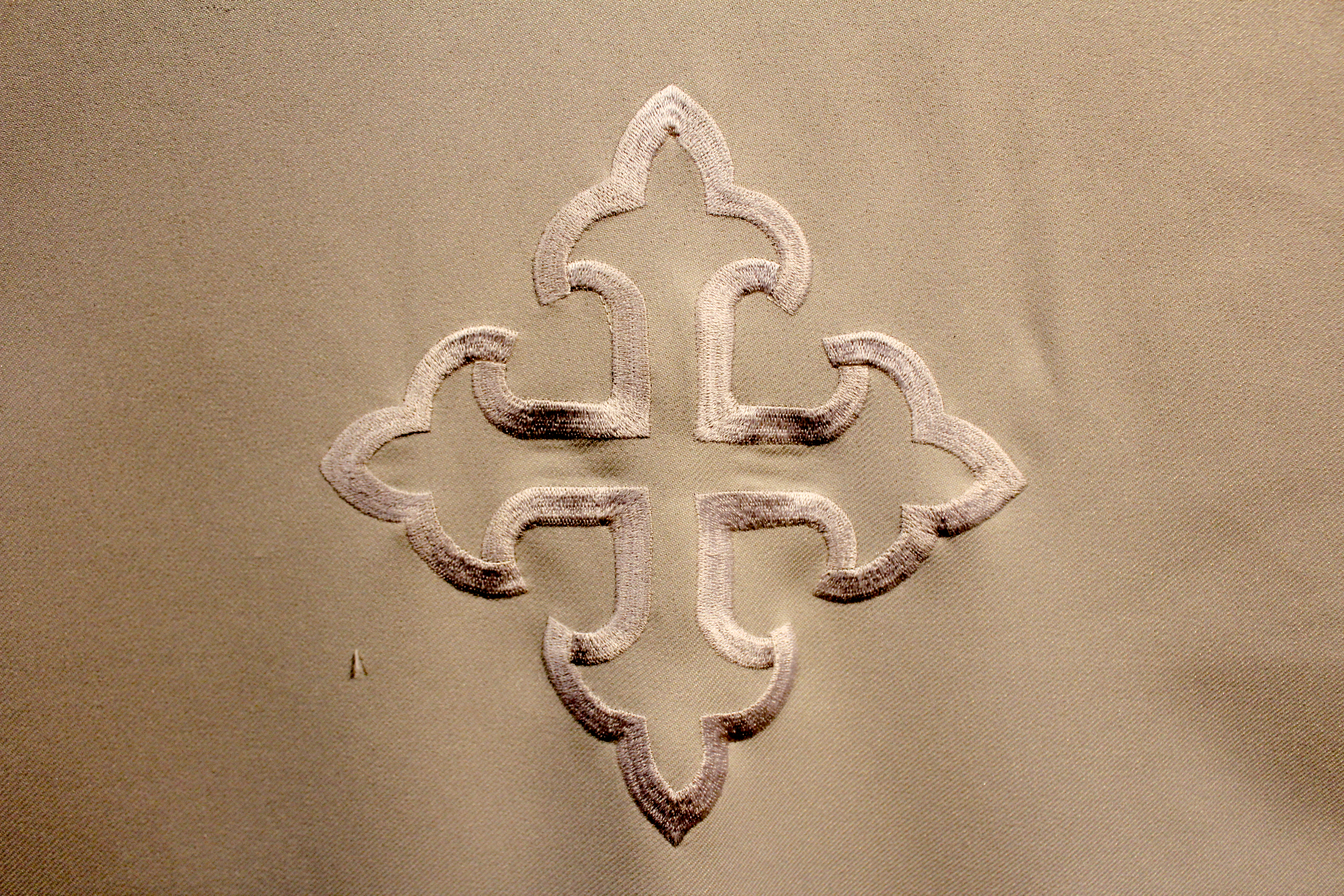 An embroidered white cross on a white cloth